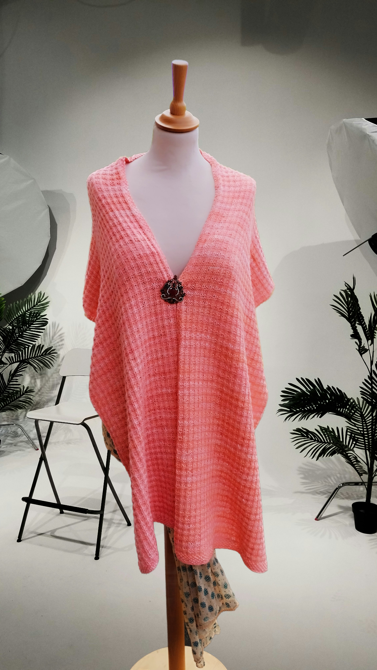 Châle rose sur mannequin dans un décor épuré.