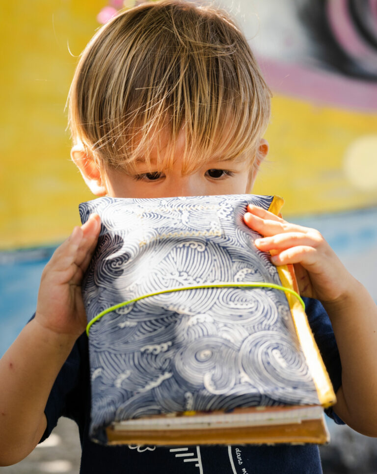 Un enfant caché derrière un carnet de croquis ouvert.
