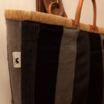 Sac artisanal vertical en patchwork de denim et tissu noir avec poignées en cuir.