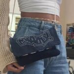 Pochette en jean bleu avec graffiti style street-art portée à la taille.
